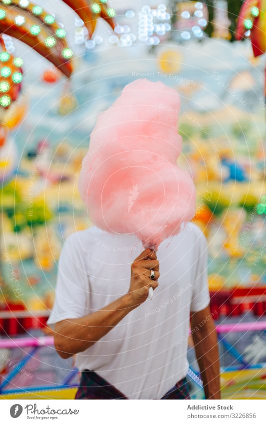 Content man enjoying cotton candy at funfair eat hipster amusement park delighted content happy bearded stand adult colourful bright neon lights summer modern