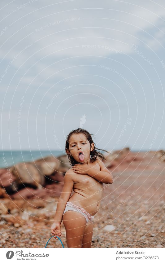 Smiling girl playing on rocky beach summer watering can vacation walking child holiday fun sea smiling ocean person active game activity shoreline little kid