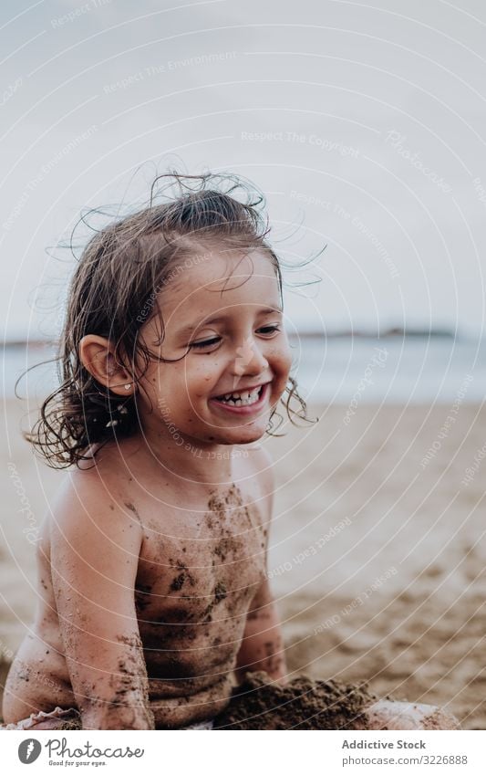 Inspired child playing with sand on beach summer vacation smeared digging holiday fun mouth girl game enjoyment expression activity cheerful joyful small