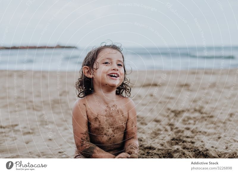 Inspired child playing with sand on beach summer vacation smeared digging holiday fun mouth girl game enjoyment expression activity cheerful joyful small