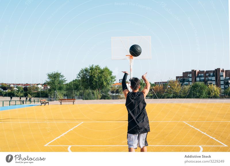 Young man playing on yellow basketball court outdoor. athlete competition sports equipment adult recreation action portrait active activity asphalt athletic