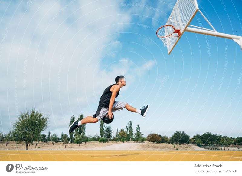 Young man playing on basketball court outdoor. athlete competition sports equipment adult recreation action portrait active activity asphalt athletic city drop