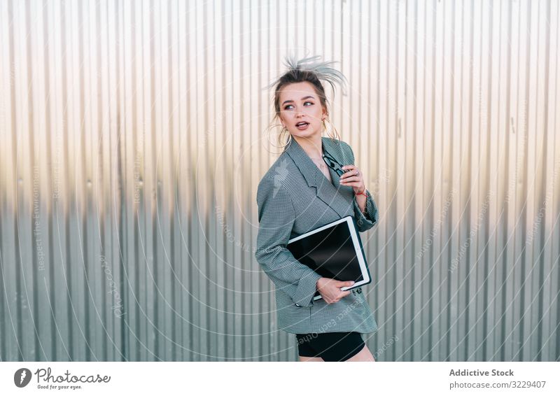 Woman with tablet in stylish suit standing nearby wall holding sunglasses businesswoman working using trendy communication manager career entrepreneur screen