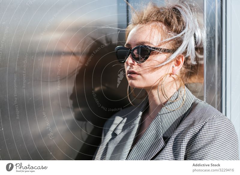 Stylish woman in black sunglasses leaning on metal wall fashion trendy model urban earring vintage grey plump retro street lady vogue jacket attractive stylish