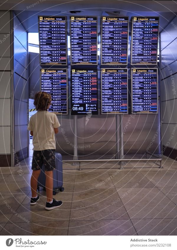 Child reading schedule in hall of airport boy suitcase scoreboard look child portugal travel tourist luggage departure arrival trip journey passenger wait