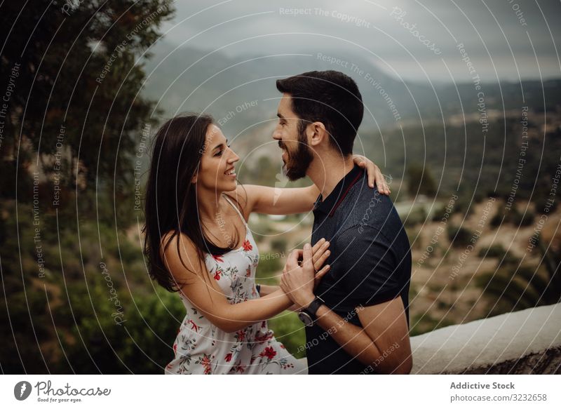 Loving couple embracing while standing against rural valley embrace love happy smile hugging countryside summer green foggy hill casual young adult nature