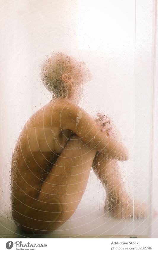 Woman behind wet glass in shower woman transparent partition bathroom water drop young female care body clean clear hygiene sensual translucent skincare routine