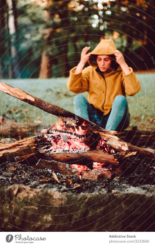 Traveling woman warming hands near campfire on forest glade tranquil flame contemplate relax solitude calm quiet silence firewood freedom enjoy serenity
