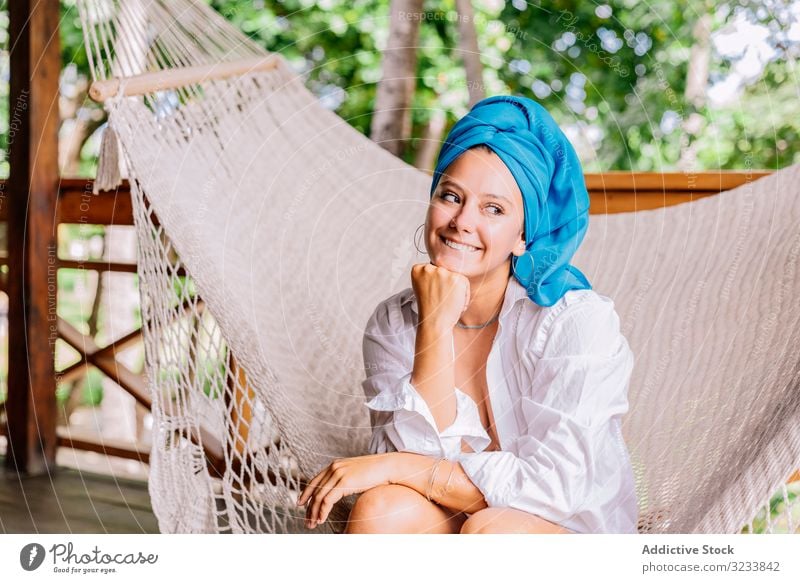 Woman in turban resting in hammock woman happy smile touching face sit terrace tree greenery shirt peaceful costa rica young relax summer comfortable lifestyle