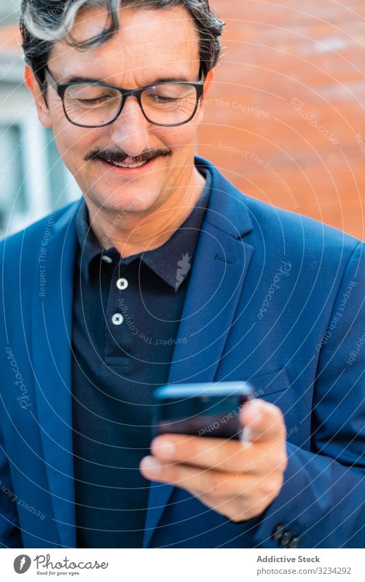 Senior businessman in blue jacket using smartphone browsing surfing mobile social media watching texting messaging adult aged senior communication internet