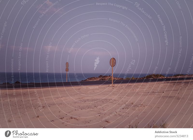 Warning signs on road along dry field and ocean seaside empty water beach warning summer tropical travel holiday motion recreation freedom emergency relaxation