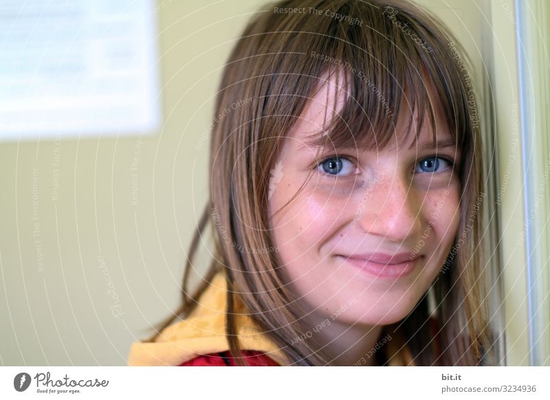 happy, happy girl with bangs and blue eyes, leaning against a wall of a building, and naturally looking into the camera with a smile. Education School Study