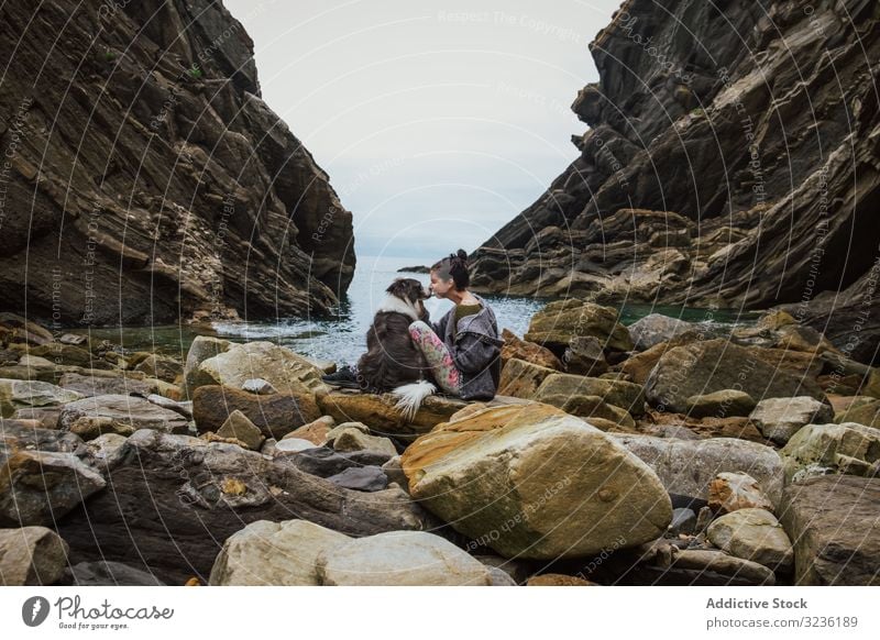 Traveling woman kissing dog sitting on boulder coast travel tourism friend border collie love bay loyalty shore happy doggy gorge tranquil environment horizon