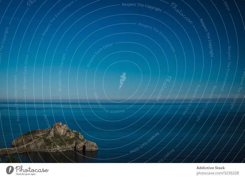 Lonely island amid sea tranquility under perfect blue sky water bay serenity solitude lonely calm coast salvation scenic idyllic environment shore freedom