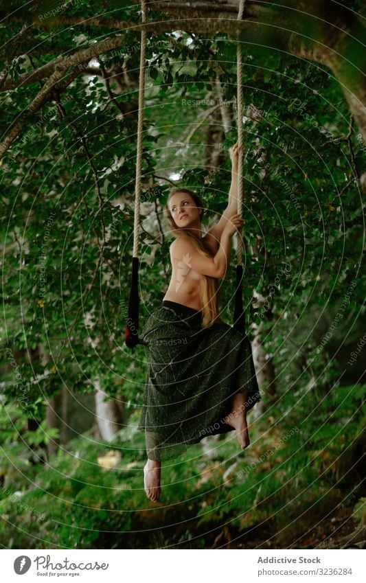Affectionate topless woman swinging at trapeze in forest concept affectionate bare gorgeous slim long hair hanging swing bar tranquil woods blonde young adult