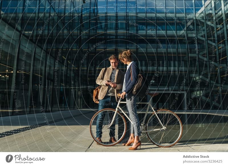 Businesspeople talking on street after work businesspeople smile building bicycle man woman colleague together couple office casual city town urban modern