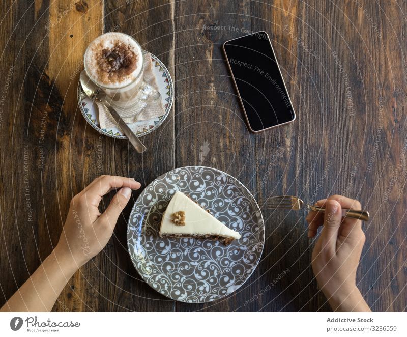 Woman eating cake in restaurant coffee table smartphone cup sweet cafe dessert delicious beverage piece tasty leisure wooden drink blank mobile screen slice