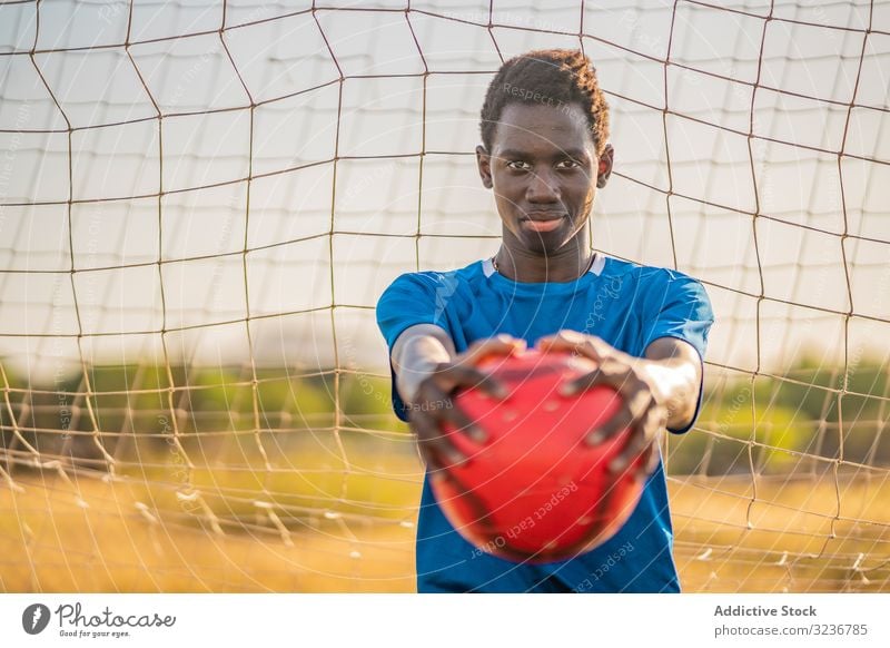 African American football player with ball teenager outstretched arms sky cloudless training sportswear ethnic show male adolescent soccer lawn black