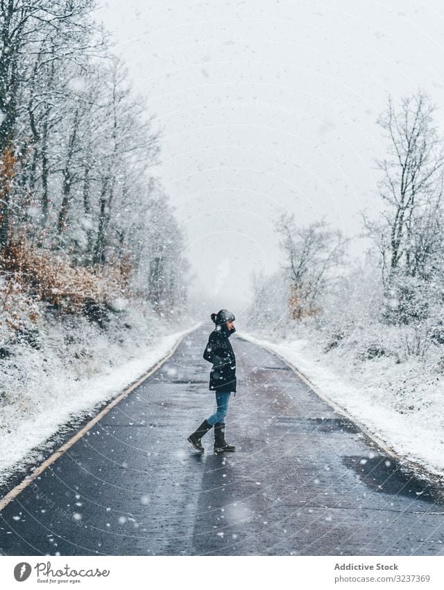 Young woman crossing winter country road snow foggy cloudy gloomy forest walk young alone lonely tree frozen cold female nature relaxation journey activity