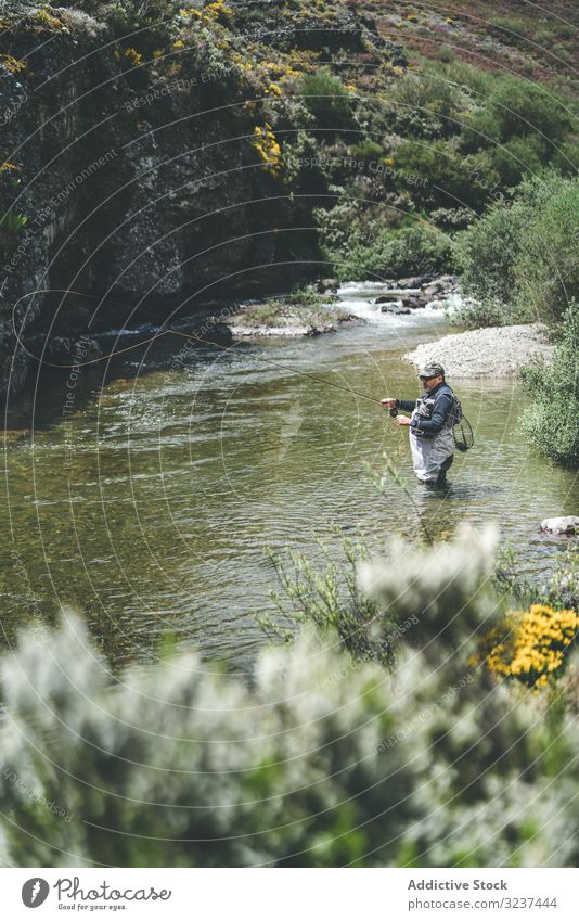 Confident man fishing with rod while standing in river stream confident equipment harling wader mountain torrent cliff forest greenery adult water fisherman