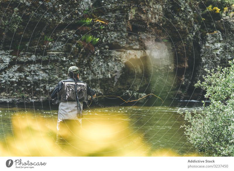 Confident man fishing with rod while standing in river stream confident equipment harling wader mountain torrent cliff forest greenery adult water fisherman