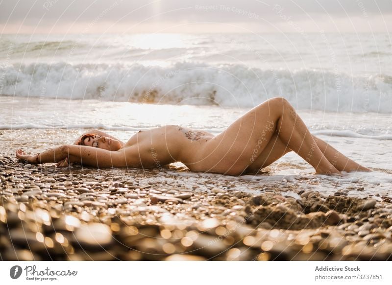 Naked woman lying down near sea waves naked nude erotic sexy sensual free seductive topless elegance breast body skin unclothed uncovered figure bare female