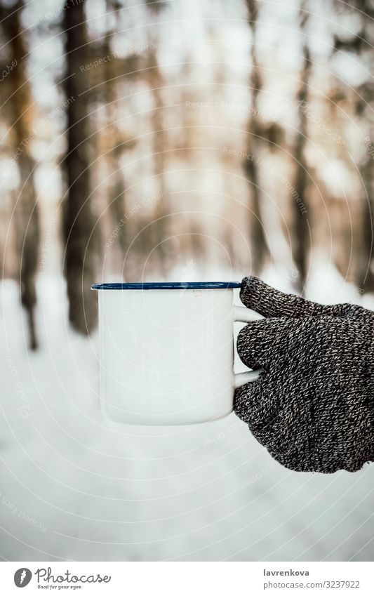 Man's hand in knitted glove holding white enamel cup Seasons Cold Common cold Gloves Knitted Nature Fresh Morning Wood Forest Exterior shot Vertical Selective