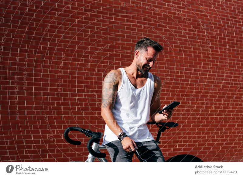Sportive man with bicycle using phone bike stand mobile phone modern sportive active summer male cyclist smartphone message texting checking reading direction
