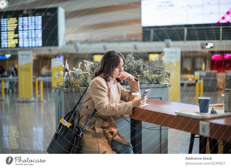 Lady sitting and using smartphone at airport woman waiting room airplane departure traveler coffee browsing terminal mobile watching surfing lifestyle texting