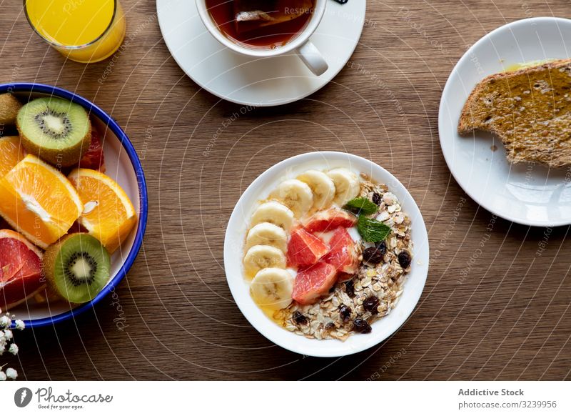 Juice and plate with granola and fruits on table juice buffet meal sliced citrus breakfast strawberry banana tea healthy muesli orange grapefruit served vegan