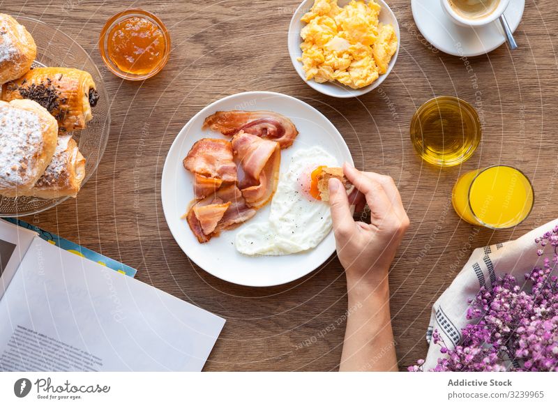 Person reading while eating bacon and eggs at table breakfast book yolk choice dip assortment food smorgasbord buffet meal nutrition fried healthy variety fresh