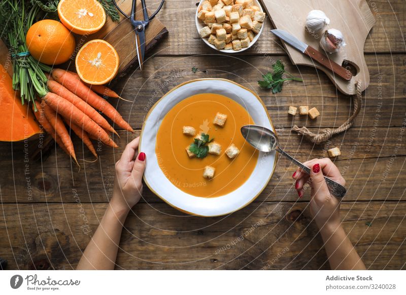 Person hands holding bowl with carrot soup cream food diet healthy vegetable orange balanced cuisine plate fresh spoon puree delicious parsley garlic vegetarian