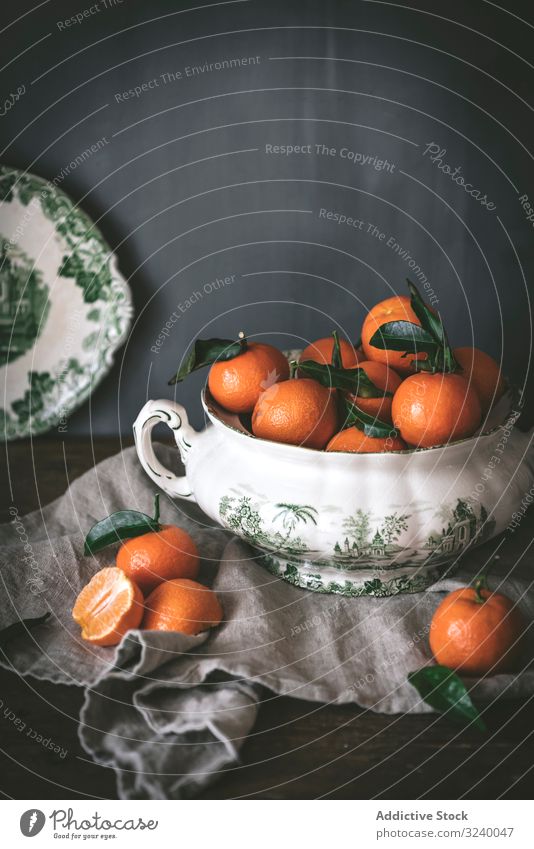 Orange tangerines in ceramic ornamental bowl on wooden table sophisticated fruit healthy classic composition still life art fresh juicy organic green tasty food