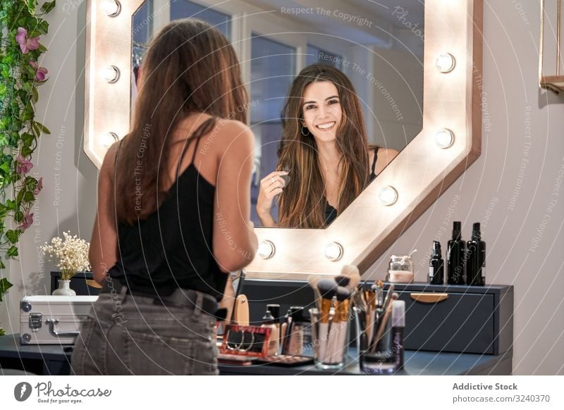 Smiling woman looking at mirror in hand in cosmetic salon reflection smiling makeup care treatment equipment style comfortable beauty interior design face
