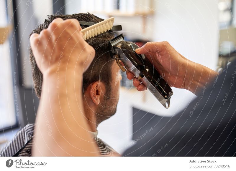 Detail of the hands of a barber cutting hair with a comb and a razor detail shaver barbershop hairstyle work service professional hairdresser arms wet man