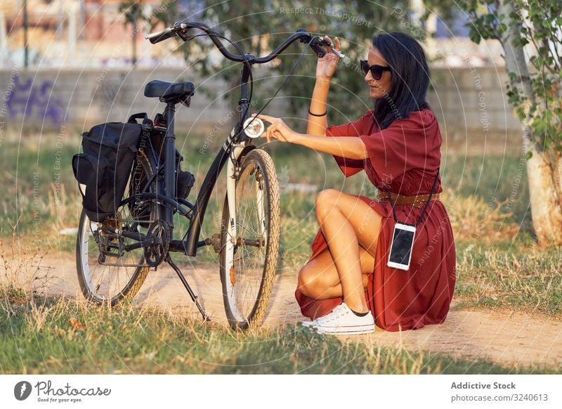 Woman fixing bike in park woman bicycle headlight path casual city summer activity female vehicle repair adjust transport lifestyle rest relax weekend lady