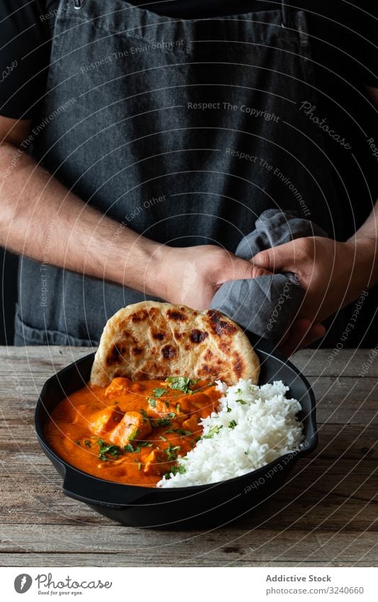 Faceless cook holding frying pan with hot butter chicken rice food dish indian cuisine curry basmati delicious gourmet traditional asian tasty meal person