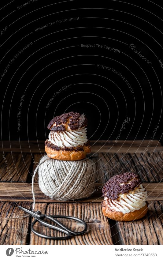Delicious choux buns and wool threads on wooden table cream pastry dessert food profiterole ball yarn scissors homemade delicious baked sweet chocolate french