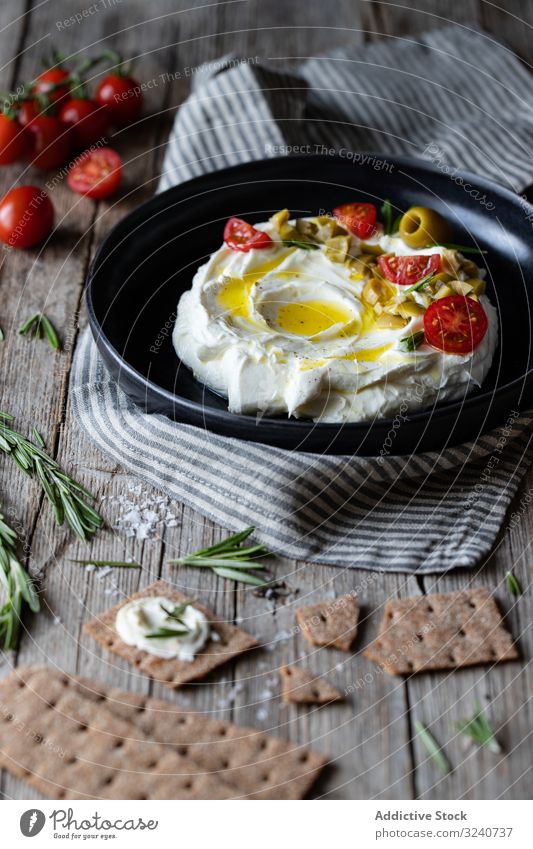 Crackers and herbs near plate with labneh cracker yogurt fresh cheese rosemary tomato olive cream greek napkin traditional cuisine meal portion dish delicious