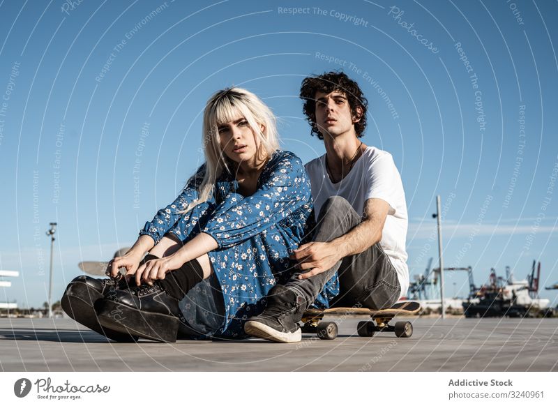 Trendy couple sitting together on skateboard on street dream support love sensual amour soulmate feelings trust calm romance square pleasure boyfriend