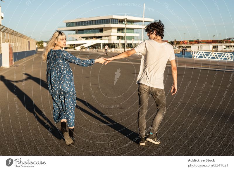 Couple holding hands while walking along road in harbor couple way relationship choose choice concept love boyfriend girlfriend curiosity trendy interest urban