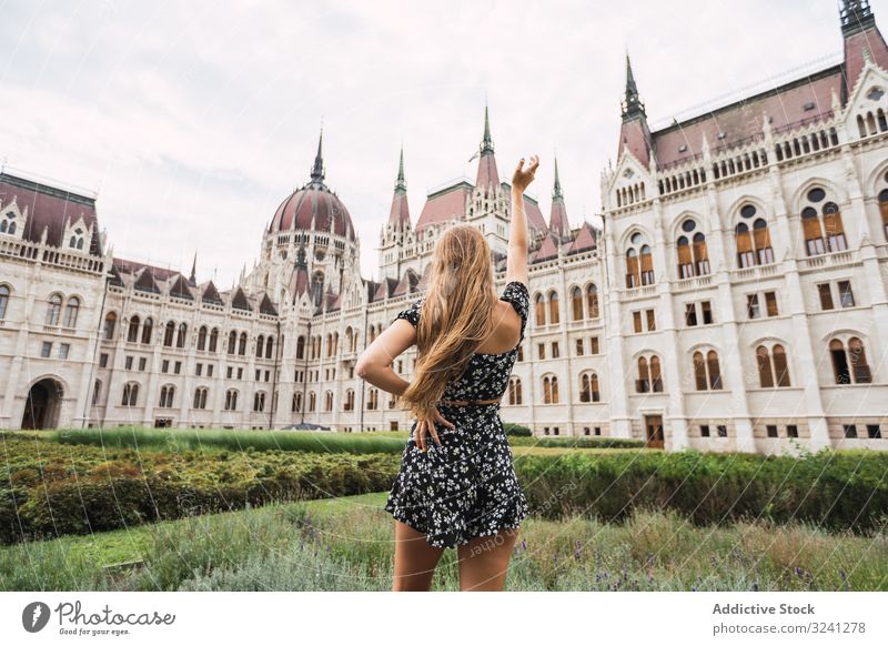 Long haired woman raising hand to ancient old building architecture palace tower tourism explore budapest hungary shape art dome travel urban city geometric