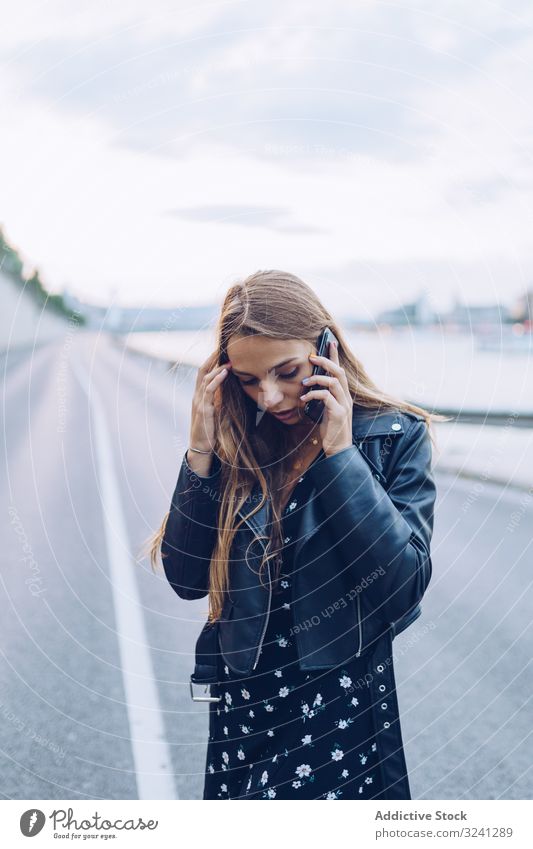 Long haired stylish woman speaking on smartphone phone call city serious news road receive budapest using focused conversation communication talking mobile