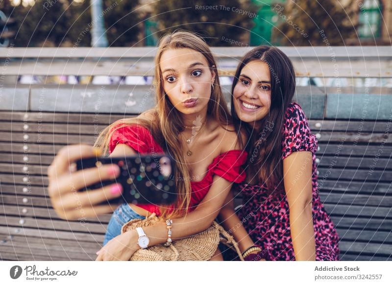 Laughing women taking selfie on wooden bench at street travel city memory using architecture building smartphone happy budapest friend friendship relationship