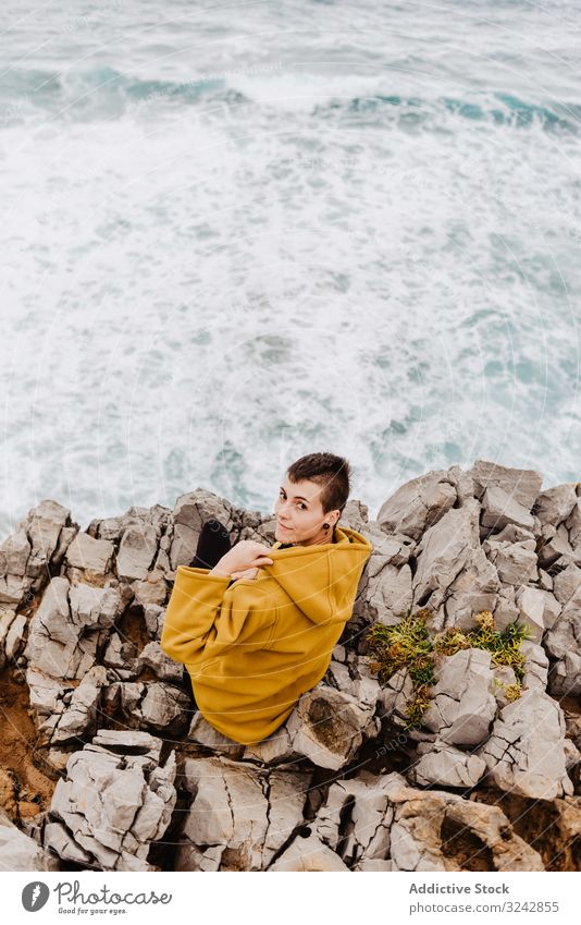 Woman in yellow hoodie on stony shore woman solitude travel wave stone watching dream harmony contemplation lonely thoughtful sea ocean horizon freedom