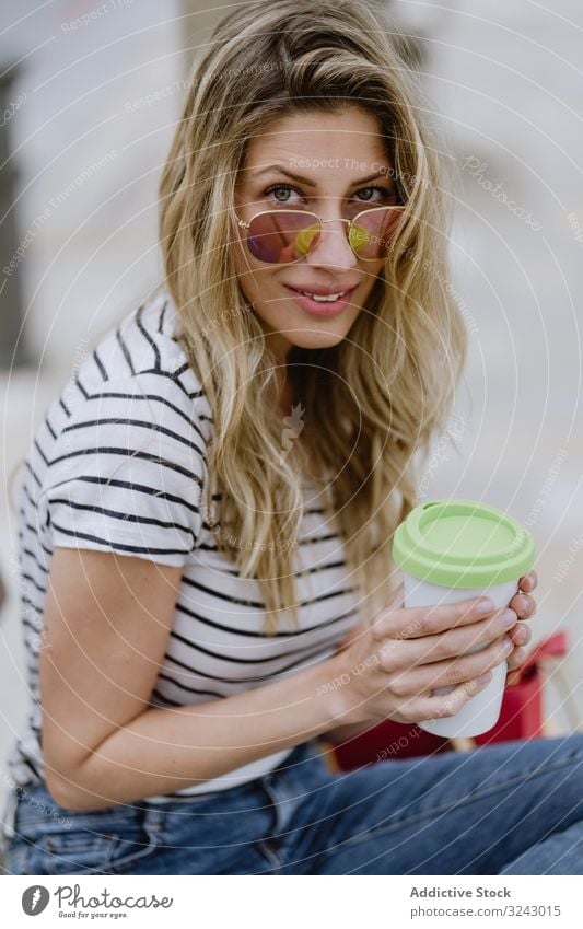 Happy woman with disposable cup of coffee sitting on street bench city seafront happy joyful enjoy casual rest young female laugh smile excited beautiful drink