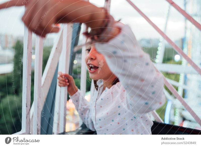 Cheerful girl riding Ferris wheel with parent ferris wheel ride excited mother fun autumn amusement park laugh kid child daughter entertainment observation
