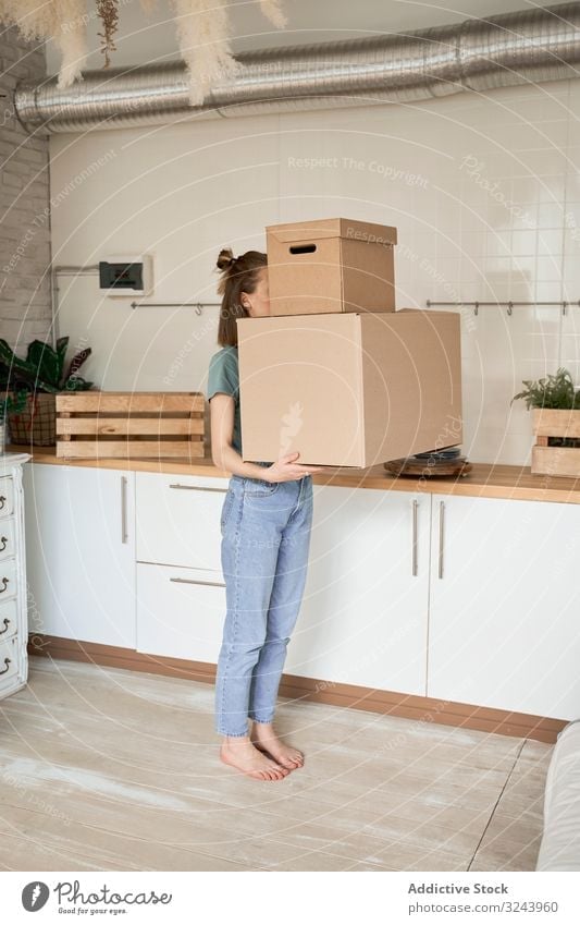 Young woman carrying big carton boxes in house container property moving female relocate home household package apartment delivery unpacking heavy parcel casual