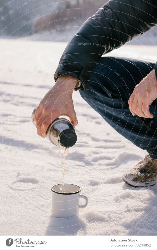 Man pouring tea from thermos bottle on winter day man snow siberia nature cold warm up russia male sit hot break rest recreation drink relax adventure activity