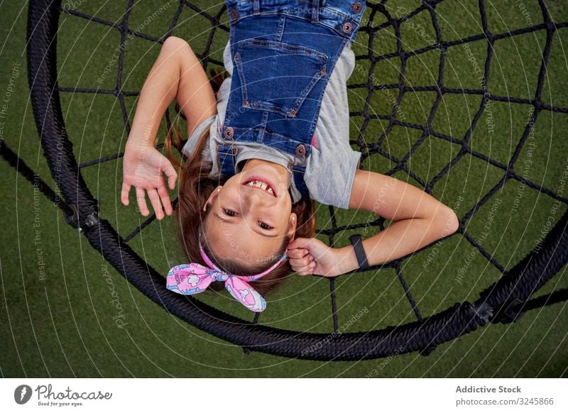 Happy girl having fun on basket swing happy play carefree teenager jumpsuit spider web lying smile playground enjoy excited playful lively child cheerful